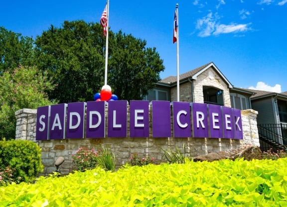 a sign for the saddle creek neighborhood in front of a house