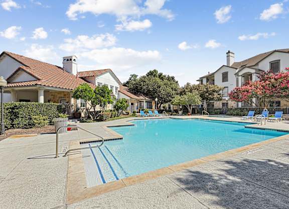 A swimming pool surrounded by a concrete floor and a metal railing.