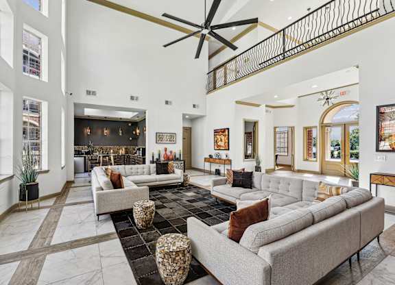 A large, modern living room with a long couch and a ceiling fan.