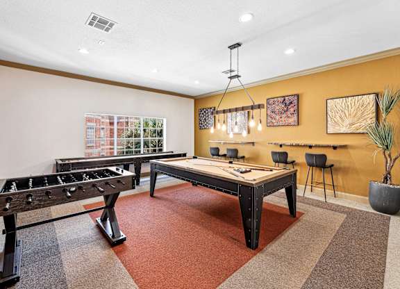 A room with a foosball table and a pool table.