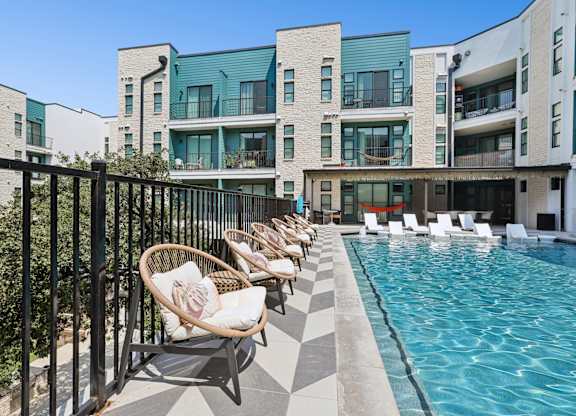 A pool area with chairs and a building in the background.