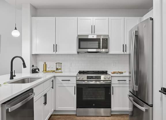 A modern kitchen with white cabinets and stainless steel appliances.