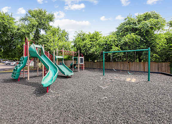 A playground with a green slide and a red slide.
