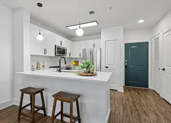 A kitchen with white cabinets and a white island with a plant on it.