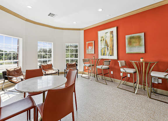A white table surrounded by brown chairs in a room with red walls.