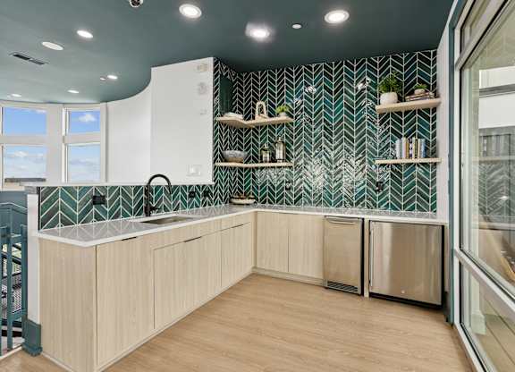 A kitchen with a green and white tiled backsplash and wooden cabinets.