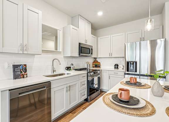 A modern kitchen with white cabinets and stainless steel appliances.
