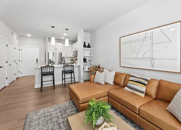 A living room with a brown leather couch and a large abstract painting on the wall.