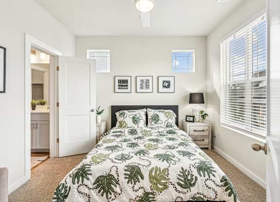 A bedroom with a large bed and a green leaf patterned comforter.