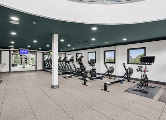 A gym with a variety of equipment including treadmills, stationary bikes, and weight machines.