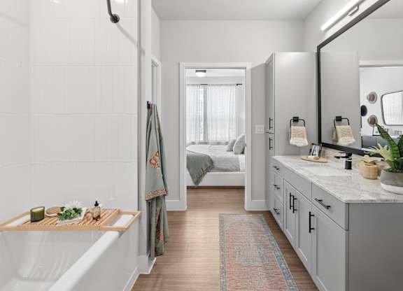 A bathroom with a white tub and a mirror.
