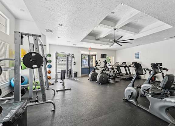 A gym with a variety of exercise equipment including treadmills, stationary bikes, and weight machines.