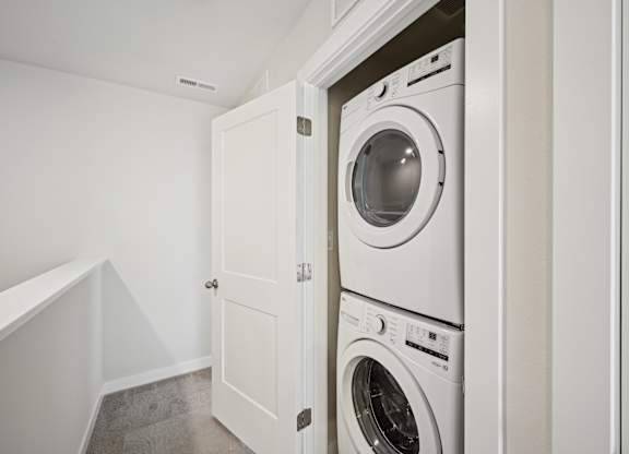 A white washing machine is in a cabinet in a room.