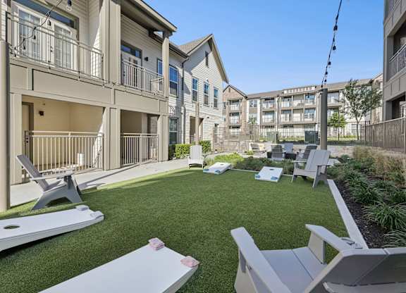 A lawn with chairs and a table in front of apartment buildings.