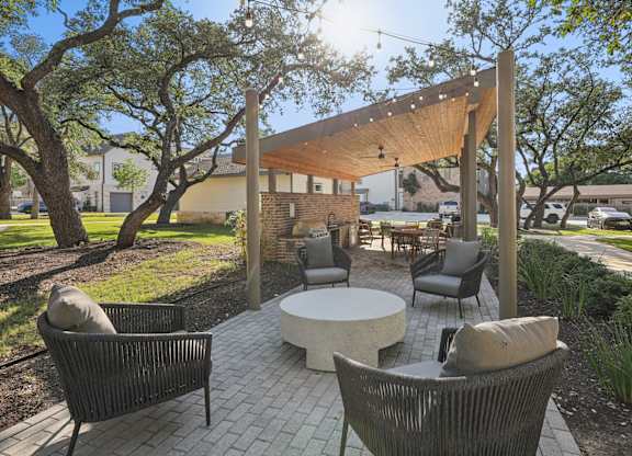 A patio with a table and chairs under a wooden pergola.