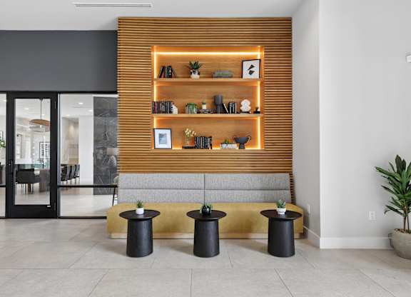 A room with a wooden bookshelf and black stools.