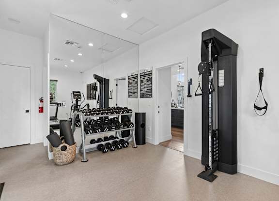 A gym room with a weight rack and a mirror.