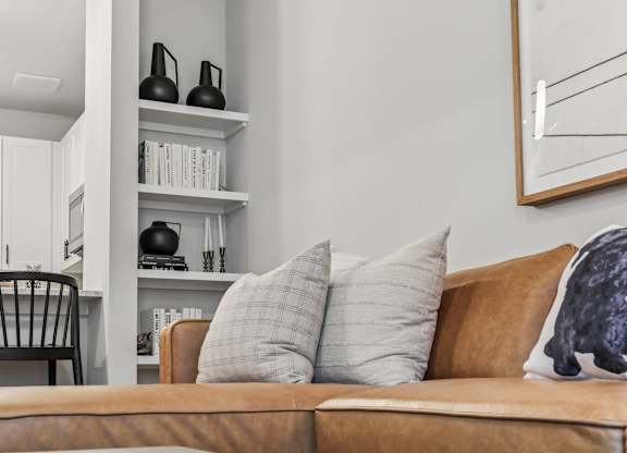 A brown couch with a grey pillow and a black sculpture on it.
