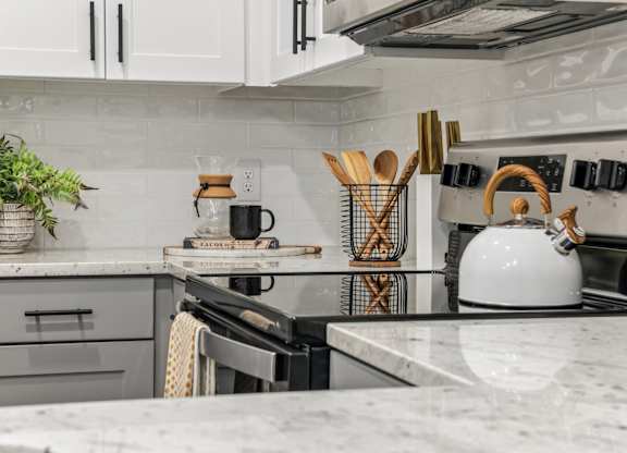 A kitchen with a white stove top oven and a white kettle on it.