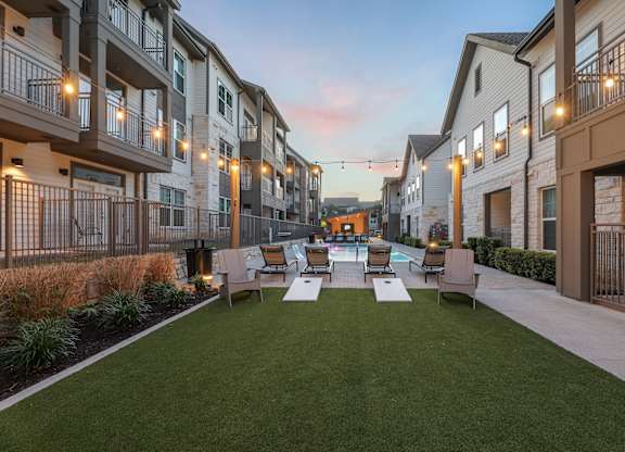 A sunny day at a residential complex with a grassy area and apartment buildings.