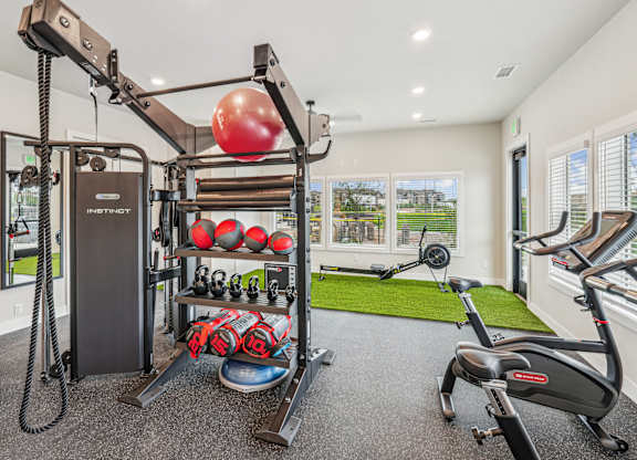 A home gym with a variety of equipment including a weight machine, a rowing machine, and a stationary bike.