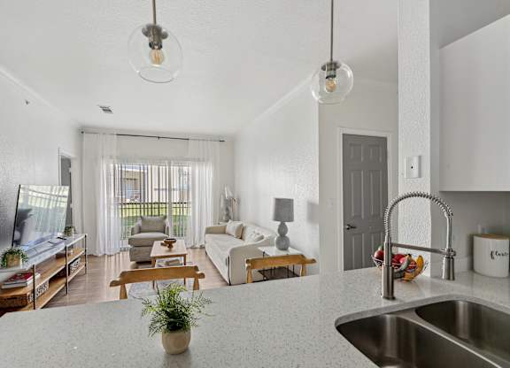 A modern kitchen with a white countertop and a stainless steel sink.