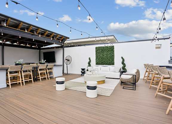 A wooden deck with a white couch and chairs.