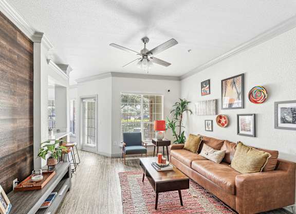 A living room with a brown couch and a ceiling fan.