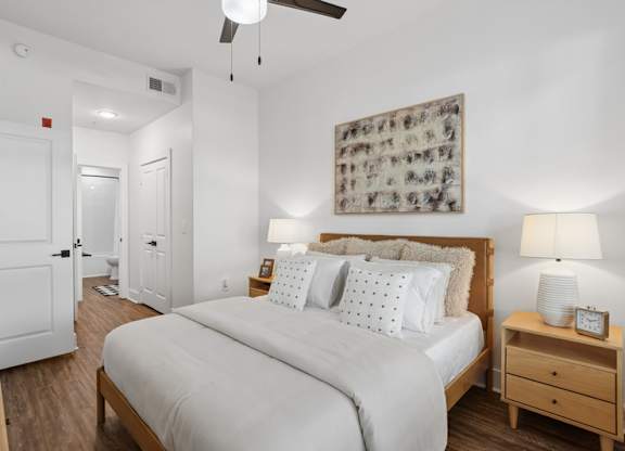 A bedroom with a large bed, a nightstand, and a ceiling fan.
