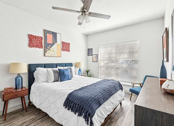 A bedroom with a bed, a ceiling fan, and a chair.