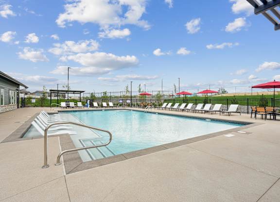 A large swimming pool with a diving board and lounge chairs.