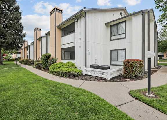 A row of apartment buildings with a green lawn in front.