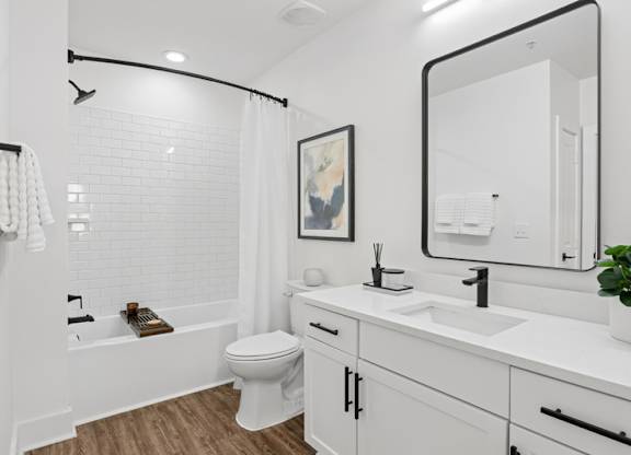A white bathroom with a toilet, sink, and mirror.