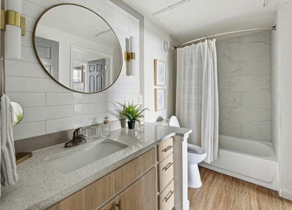 A bathroom with a sink, mirror, and shower.