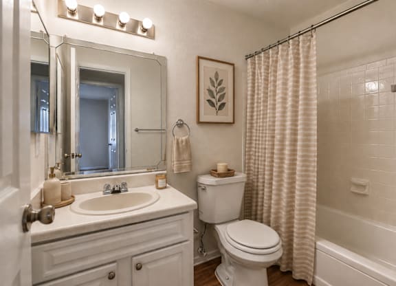 A white bathroom with a toilet, sink, and shower.