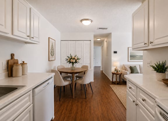 A kitchen with white cabinets and a wooden floor.