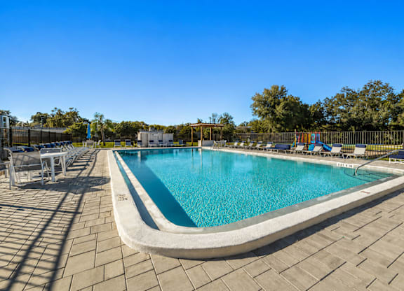 A large outdoor swimming pool surrounded by a tiled patio.