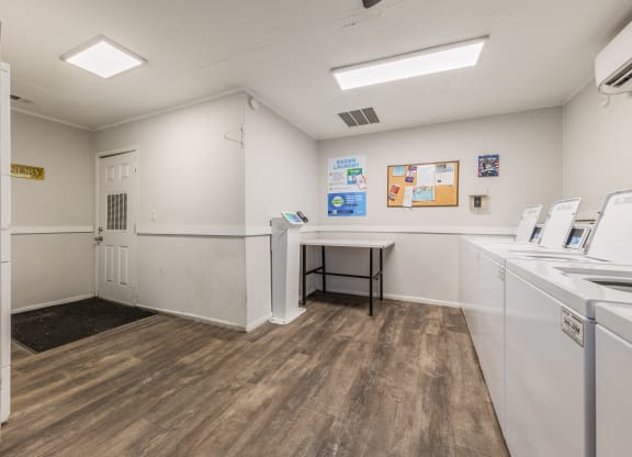 a laundry room with washers and dryers and a table with a chair