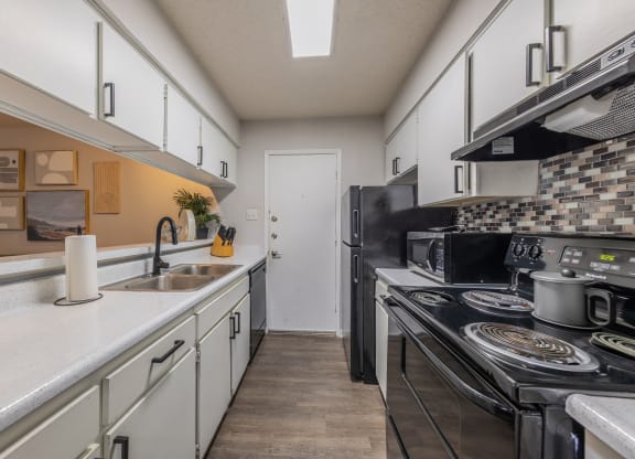 a kitchen with white cabinets and black appliances