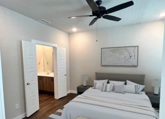 A bedroom with a large bed and a ceiling fan.