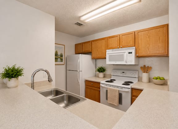 A kitchen with a sink, stove, and refrigerator.