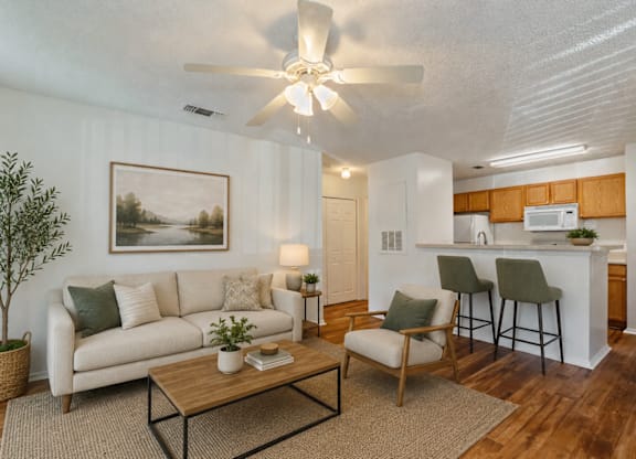 A living room with a white couch, a coffee table, and a painting on the wall.