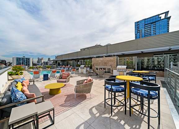 a rooftop patio with tables and chairs and a city in the background