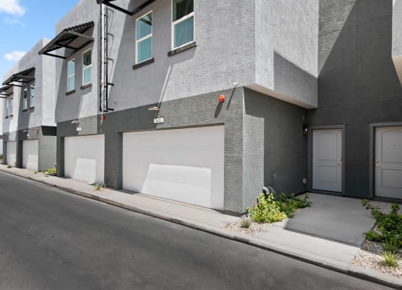 a street view of a gray building with white garage doors
