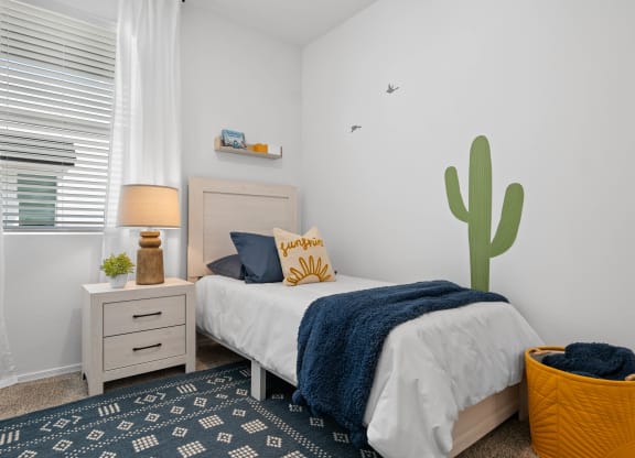 a bedroom with a bed and a cactus mural on the wall
