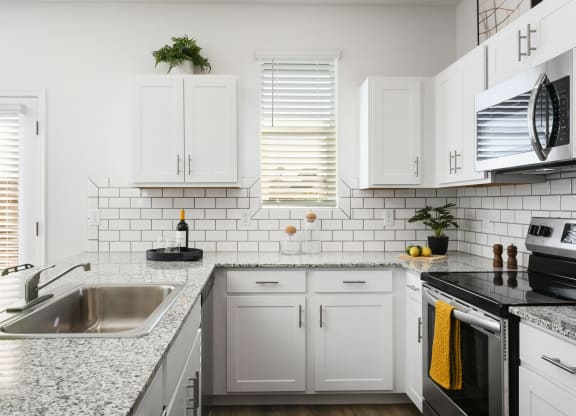 a kitchen with white cabinets and granite counter tops and a sink