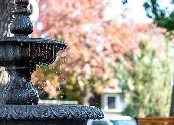 a water fountain in a park next to a bench