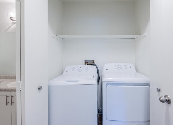 Two white front loading washing machines in a small laundry room.