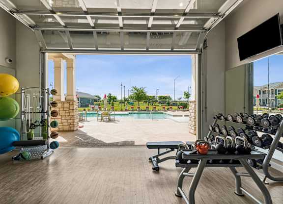 A gym with a view of a pool and a playground.