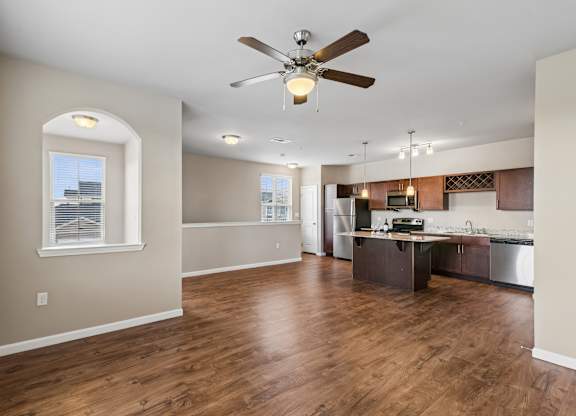 A spacious kitchen and living room with hardwood floors and a ceiling fan.